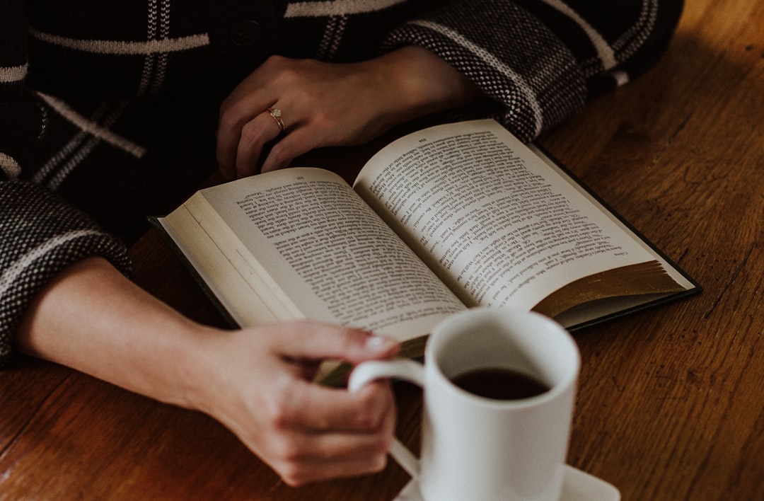 seseorang membaca buku dengan serius di meja dengan secangkir kopi